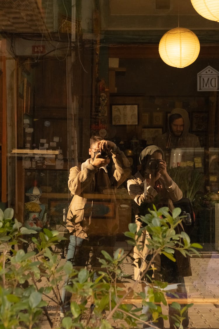 Unrecognizable Couple Taking Pictures Of Reflection In Shop Window