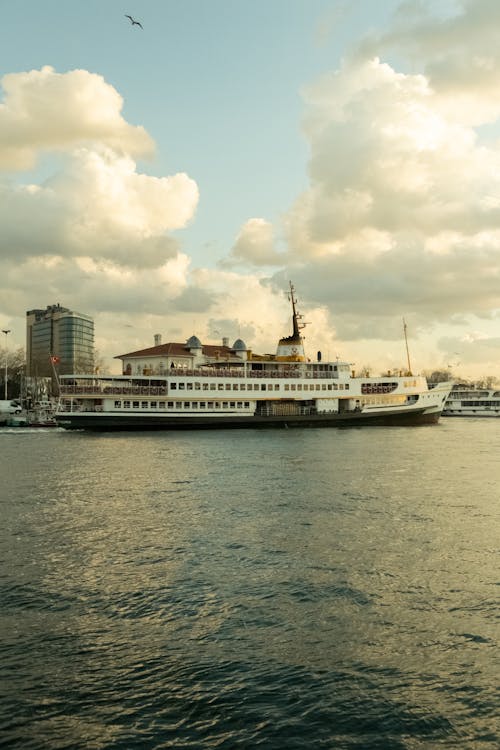 Modern ship sailing on river under cloudy blue sky