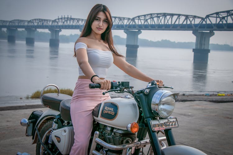 Woman In White Off Shoulder Riding On Motorcycle Near Body Of Water