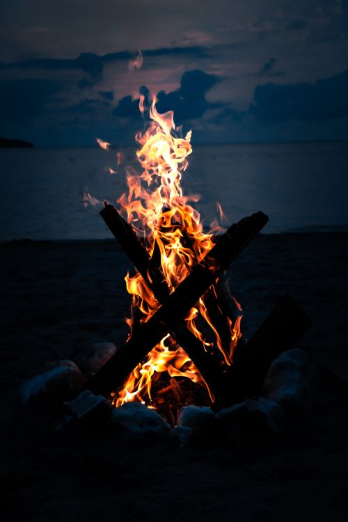 Free A warm campfire on a serene Turkish beach, surrounded by night sky and sea. Stock Photo