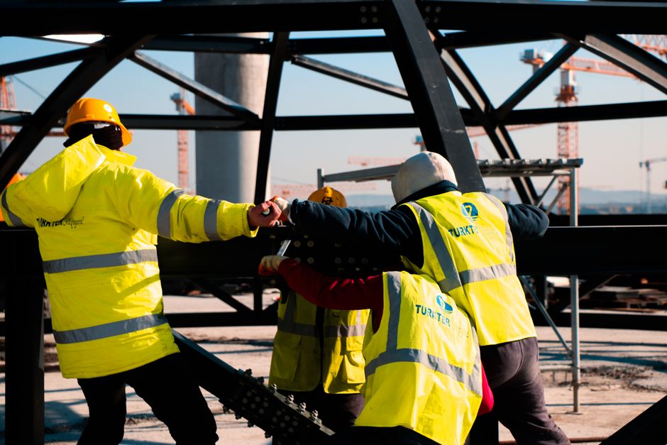 Equipo de construcción en Turquía trabajando en la estructura de acero, mostrando seguridad y trabajo en equipo.