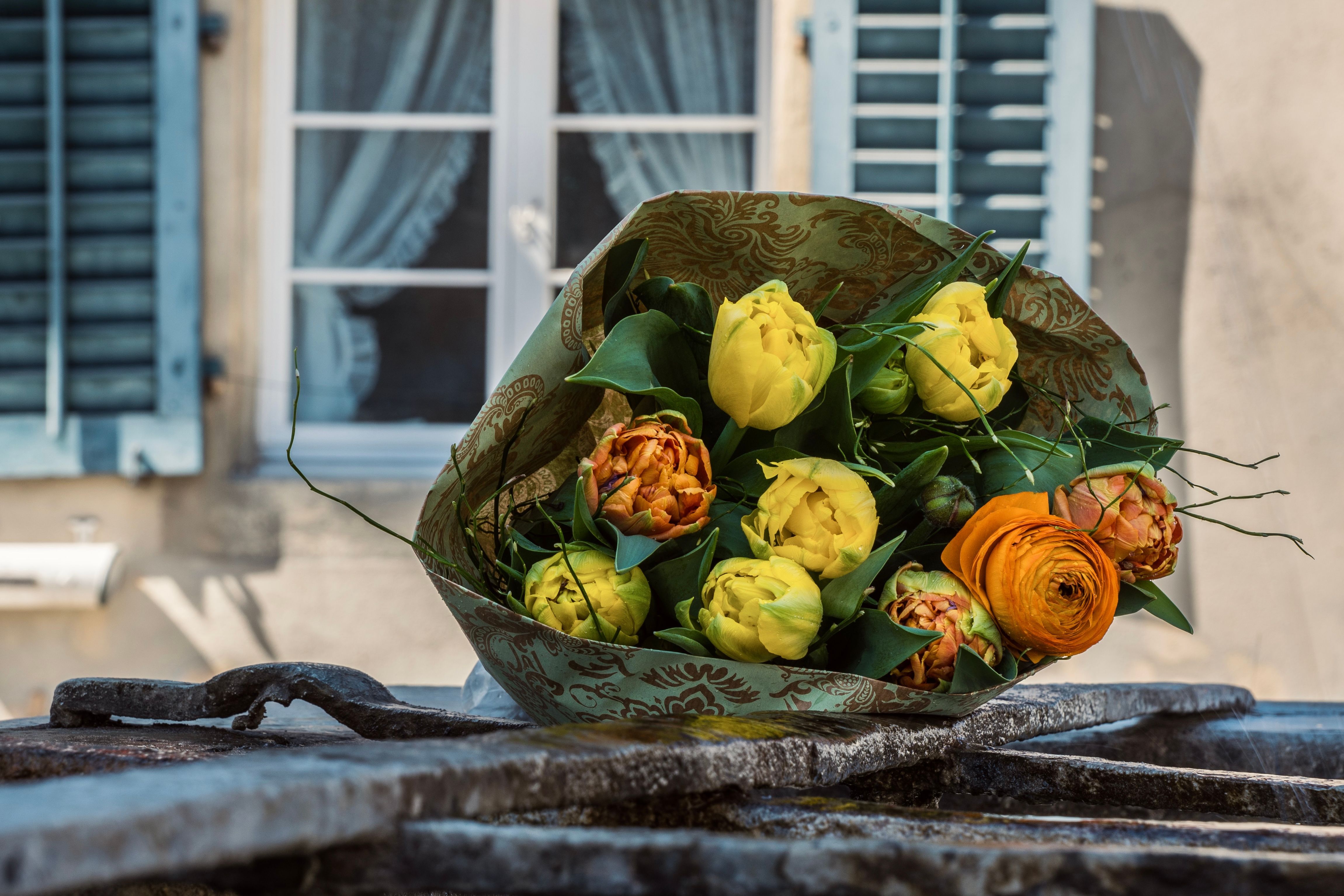 Elegant bouquet of yellow and orange flowers against a charming window backdrop.