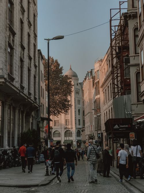 Free A vibrant city street capturing people, buildings, and historical architecture in warm daylight. Stock Photo