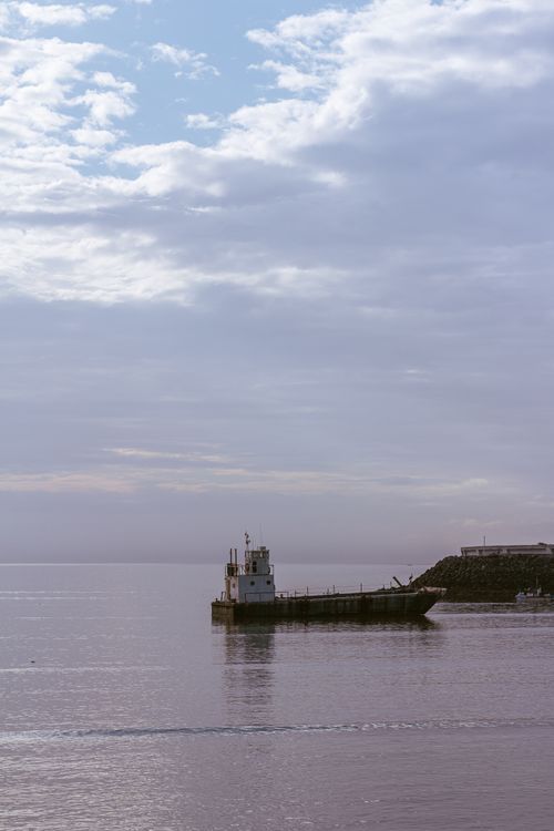 Free Calm ocean scene with a lone ship and expansive sky, capturing tranquility. Stock Photo