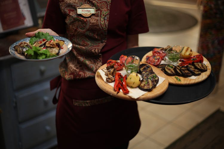 Waitress Holding Plates With Roasted Vegetables