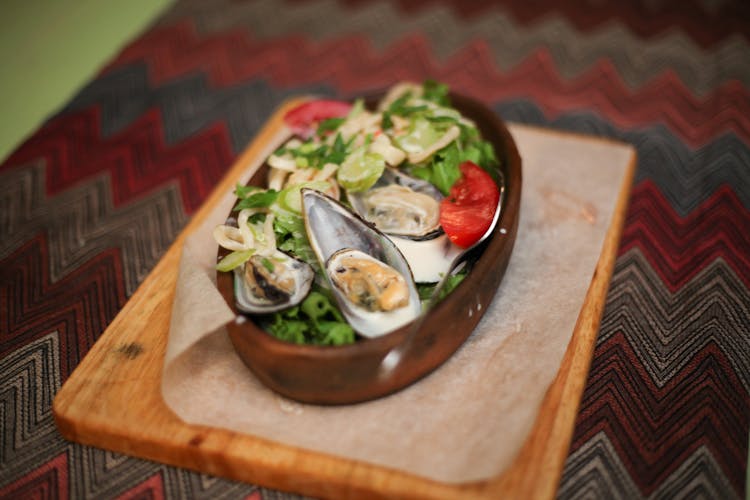 A Mussels Dish On A Brown Wooden Chopping Board