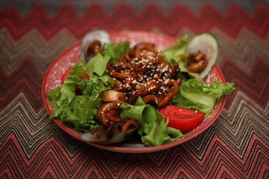 Close-up of a seafood salad with fresh lettuce, tomatoes, and mussels on a decorative plate.