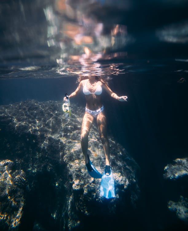 Anonymous woman diving in sea on sunny day