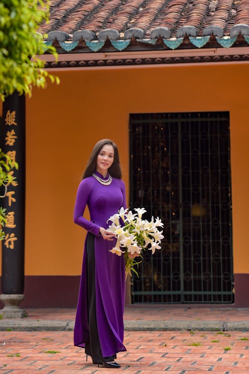 Free Photo of a Woman in a Purple Dress Holding a Bouquet of White Flowers Stock Photo