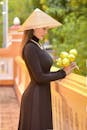 Photo of a Woman in a Black Dress Wearing an Asian Conical Hat