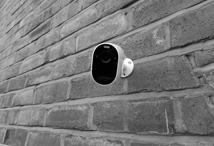 Monochrome Photo Of A Surveillance Camera On A Brick Wall