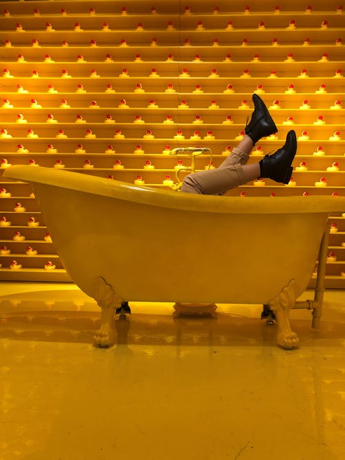 A Person in Brown Pants and Black Leather Shoes Lying on the Bathtub
