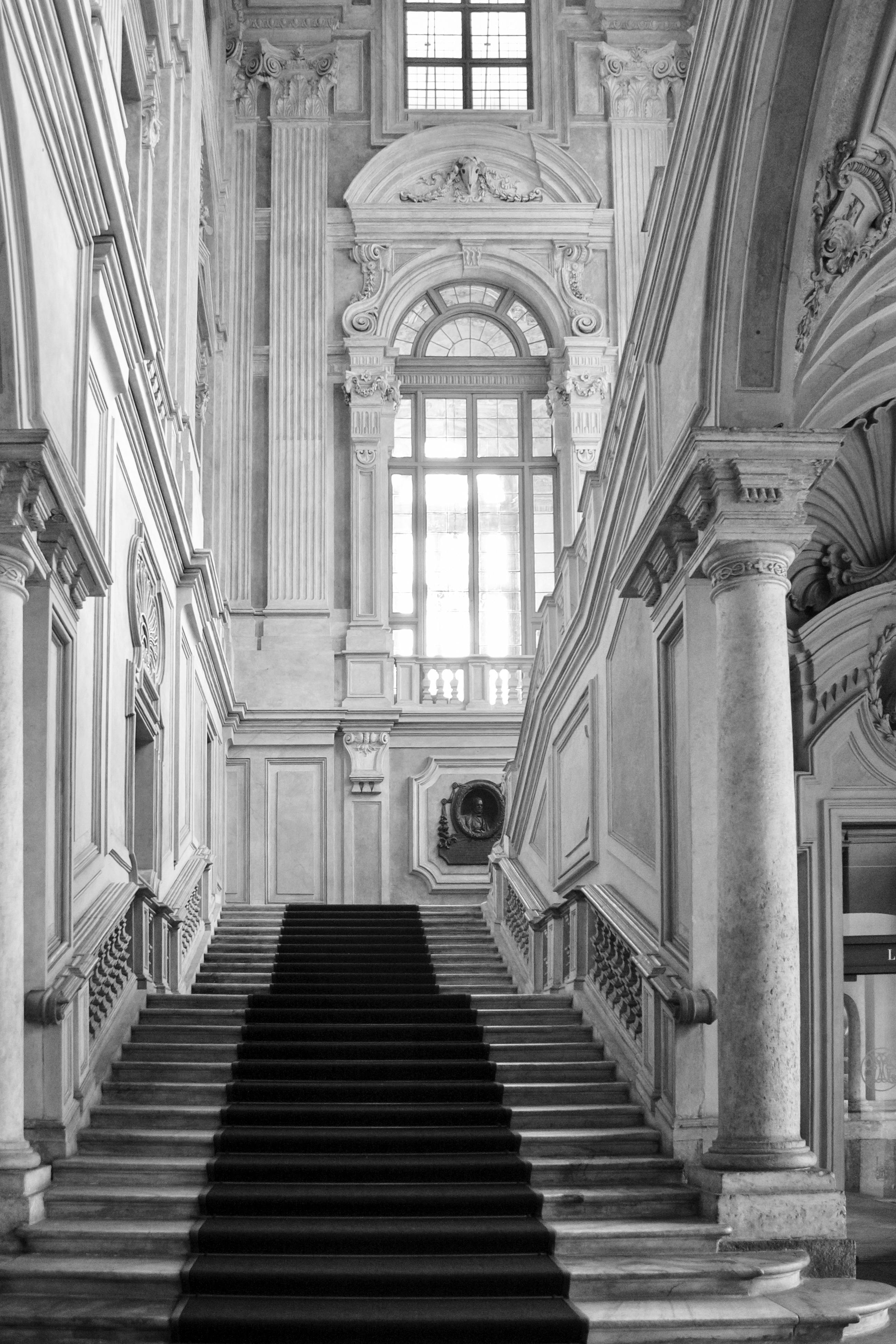 Black and white photo of an ornate staircase inside an Italian historical building in Torino.