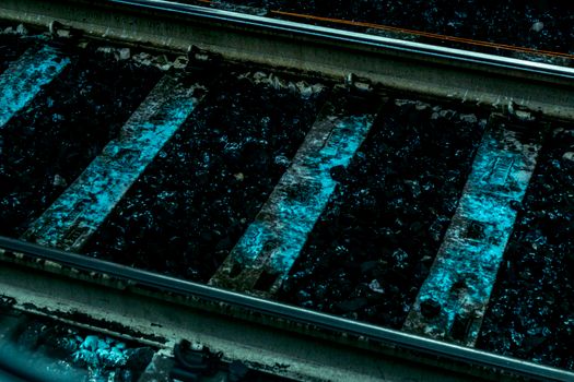 Detailed close-up of weathered, rusty railroad tracks with a blue tint.