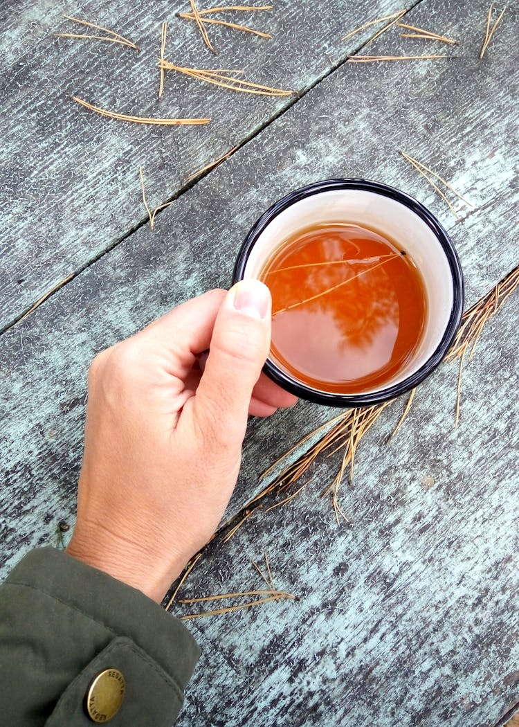 Person Holding Black And White Ceramic Coffee Cup Filled With Coffee