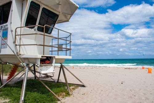 Free Lifeguard tower on a sandy beach with blue skies and ocean waves. Stock Photo