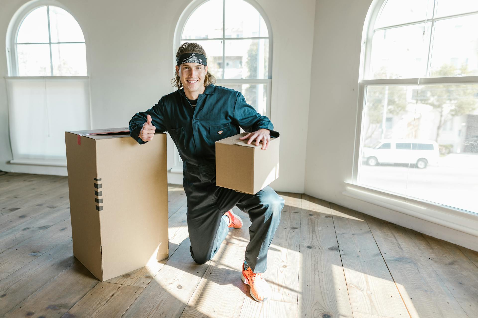 Smiling man indoors with cardboard boxes, representing a move into a new home. Bright and cheerful.