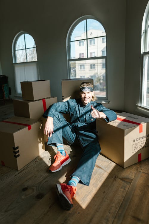 Free Man Sitting on the Floor Next to Cardboard Boxes Stock Photo