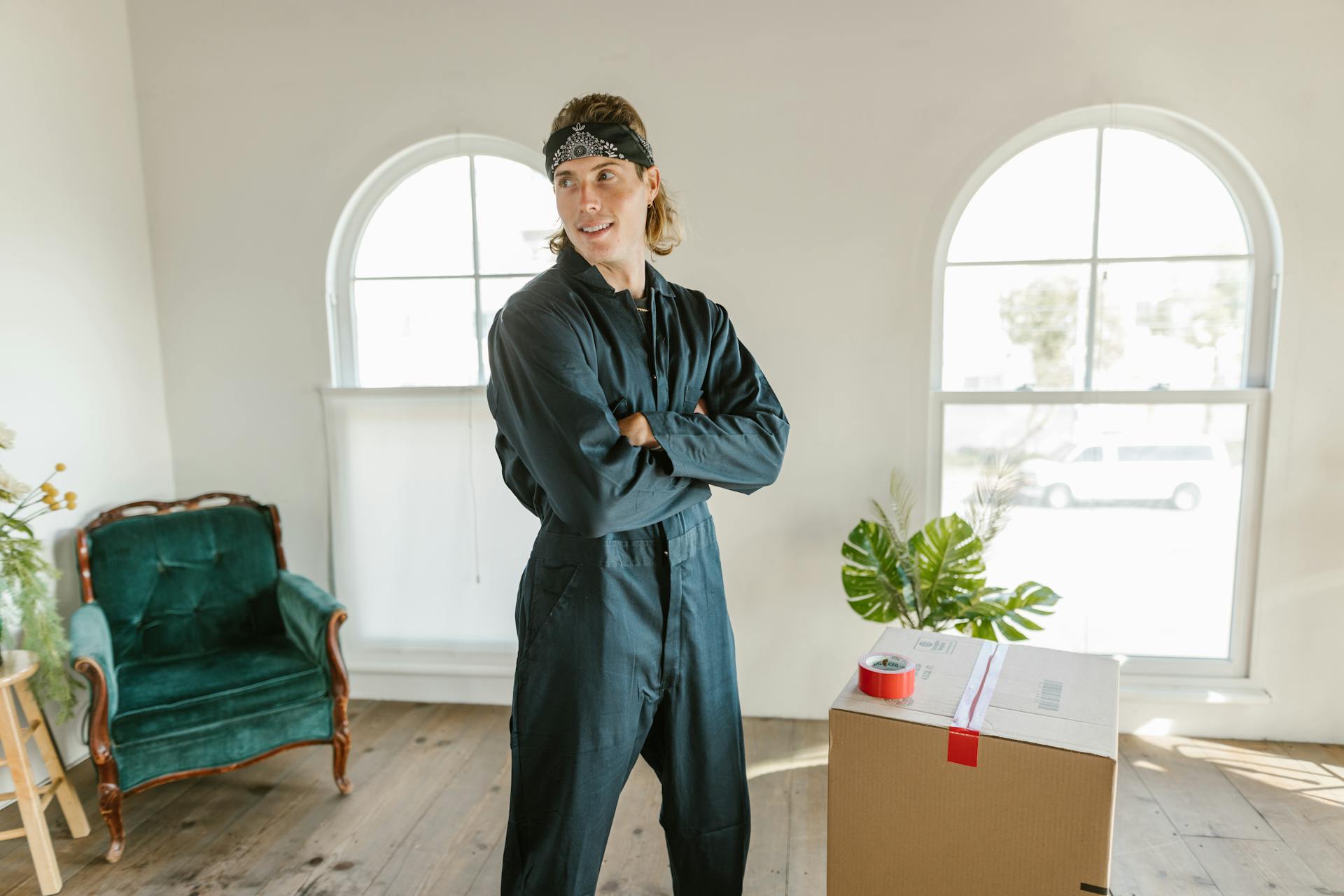 Man in a jumpsuit smiling in a new home with moving boxes.