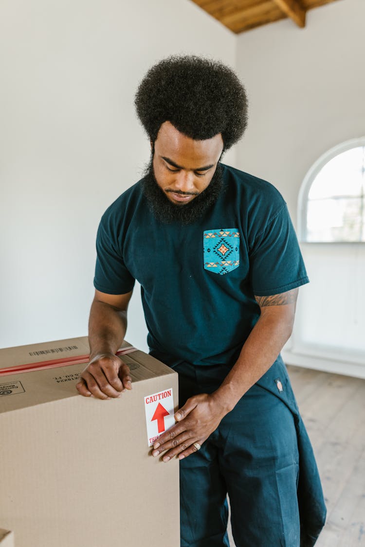 Bearded Man Putting Caution Sticker On Moving Box 