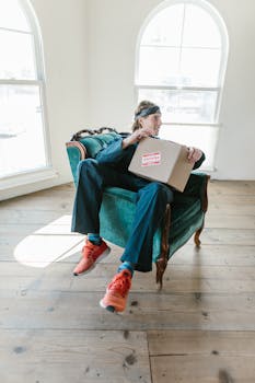 Casual young man sitting indoors holding a delivery box with 'Fragile' label.