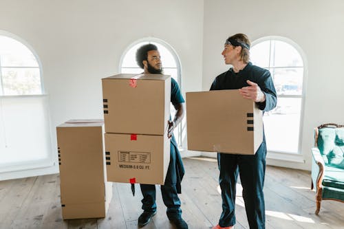 Men Carrying Cardboard Boxes while Having a Conversation