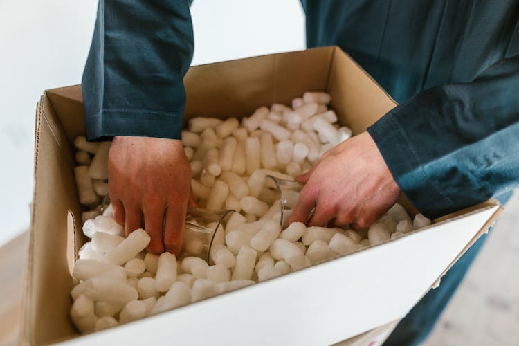 A Person Putting The Glasses In A Box Full Of Polystyrene Foam