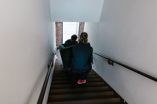 Free Two men carefully move a couch down a staircase in an indoor setting. Stock Photo
