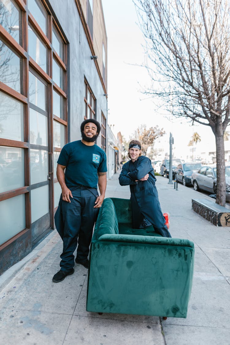 Two Men Posing On A Green Couch On The Sidewalk