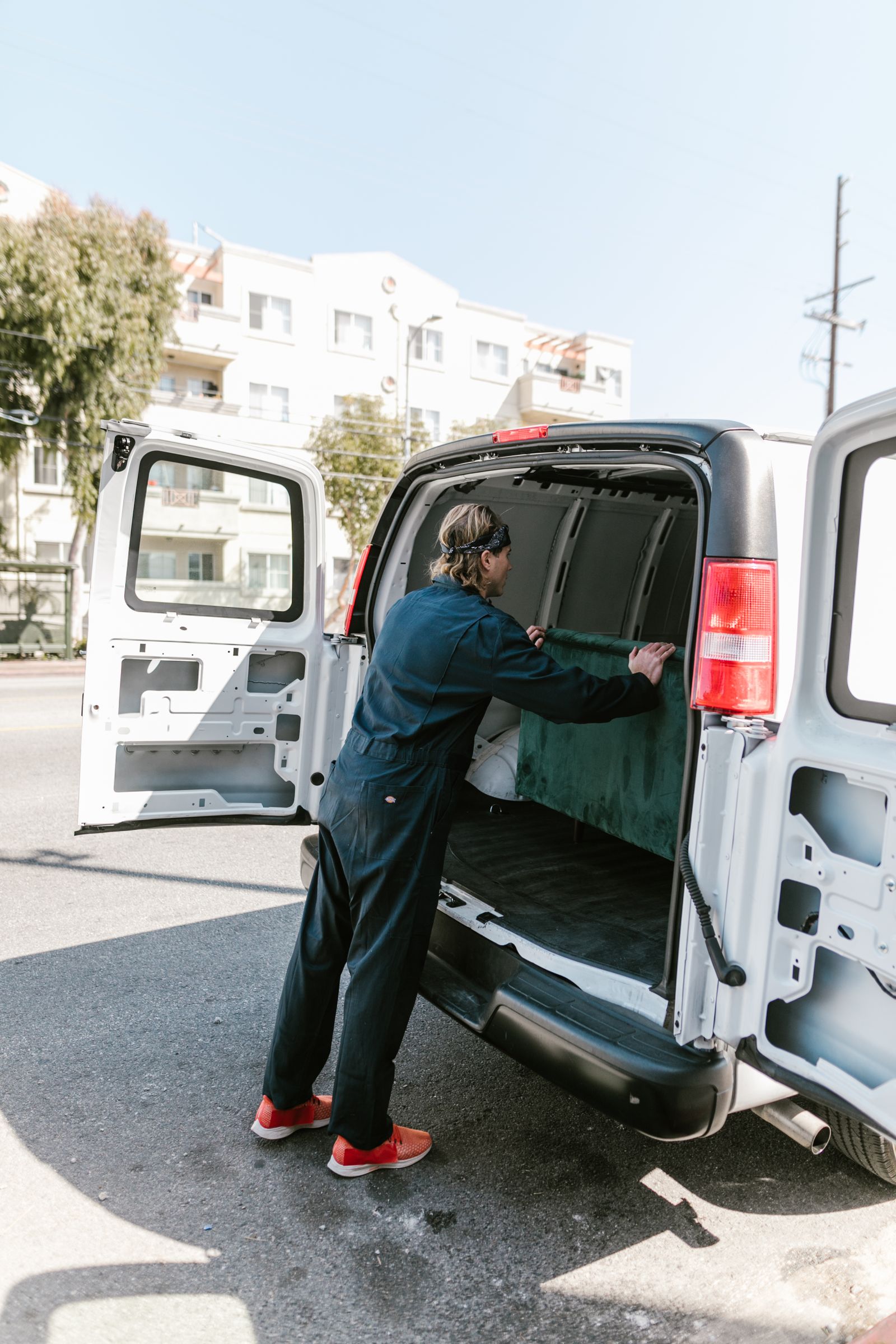 A mechanic in coveralls working at the back of a work van