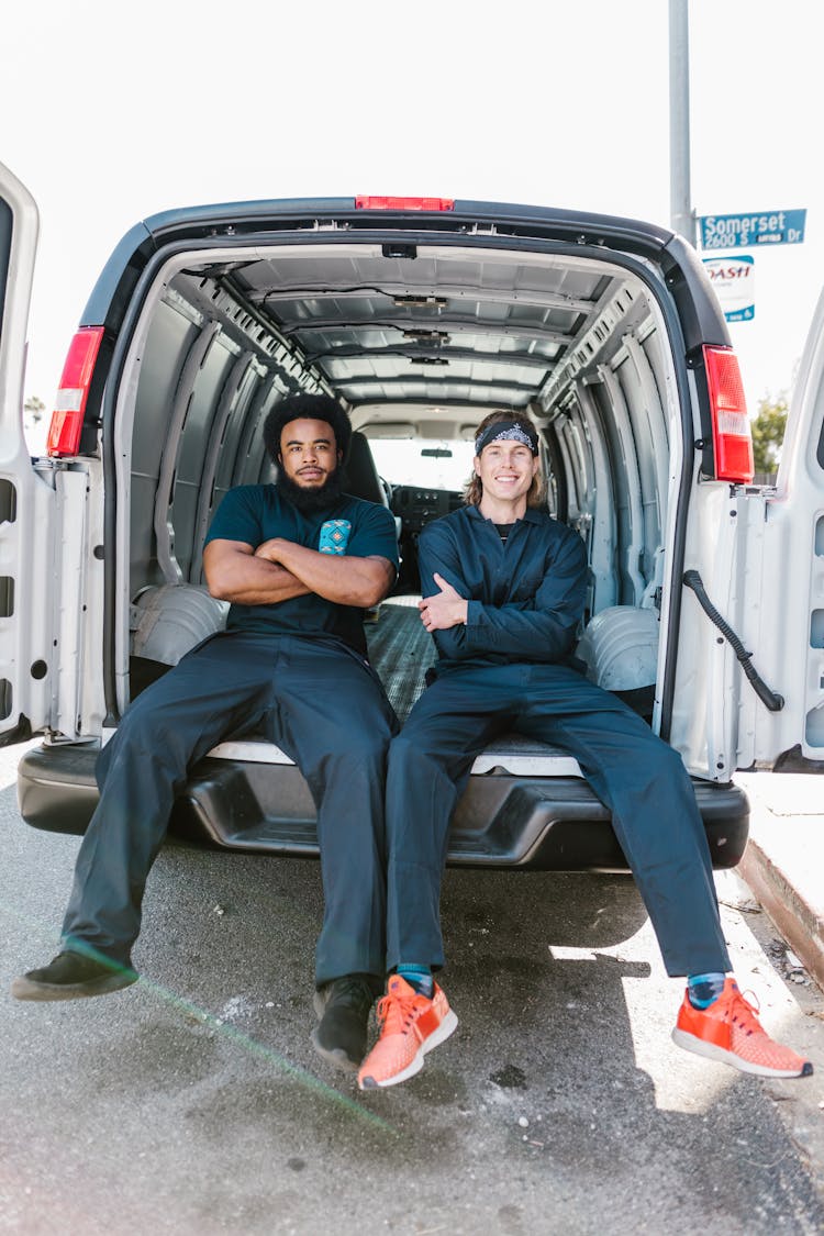 Two Men Sitting At The Back Of A Movers Van