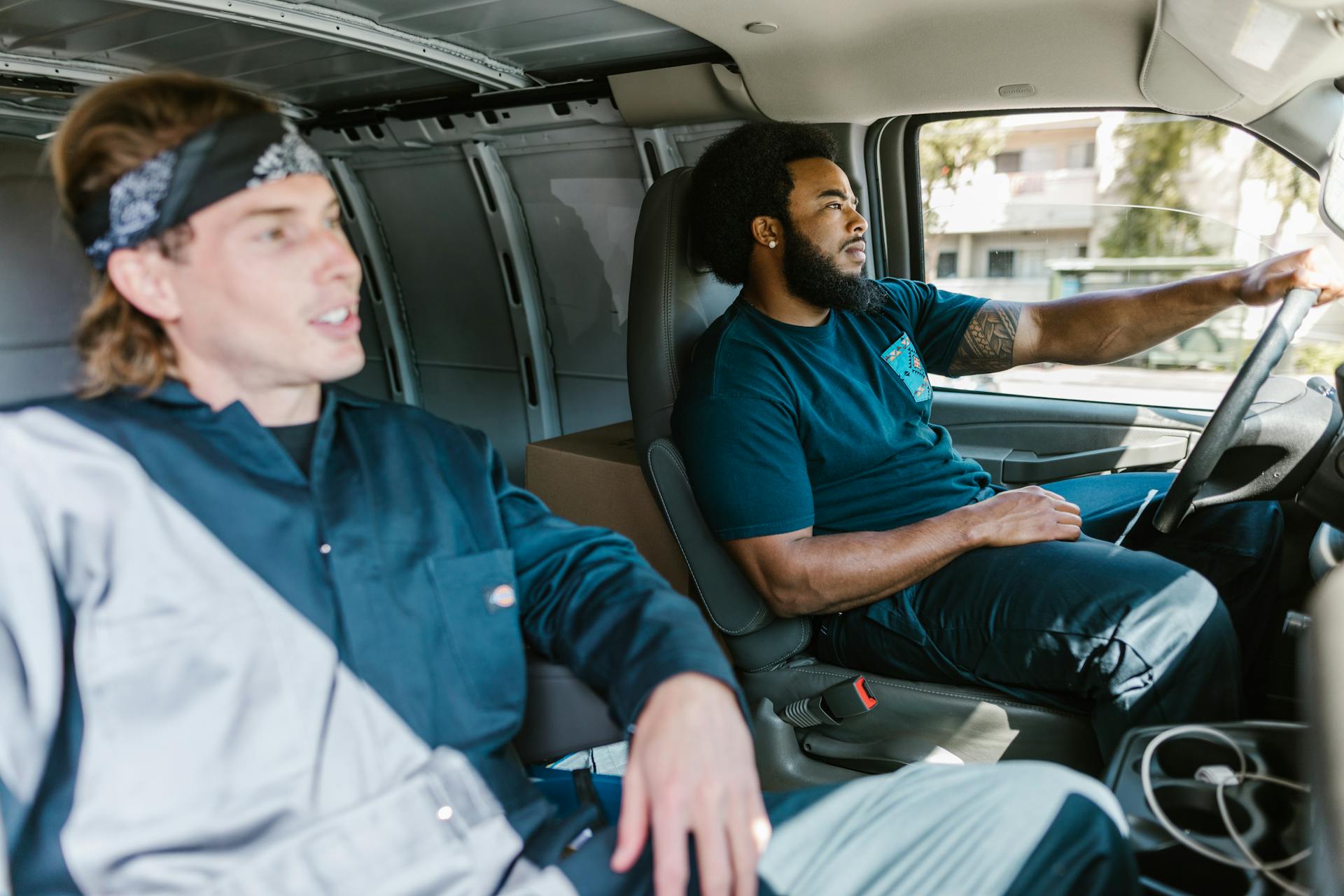 Two delivery professionals focused on their route while driving a cargo van.