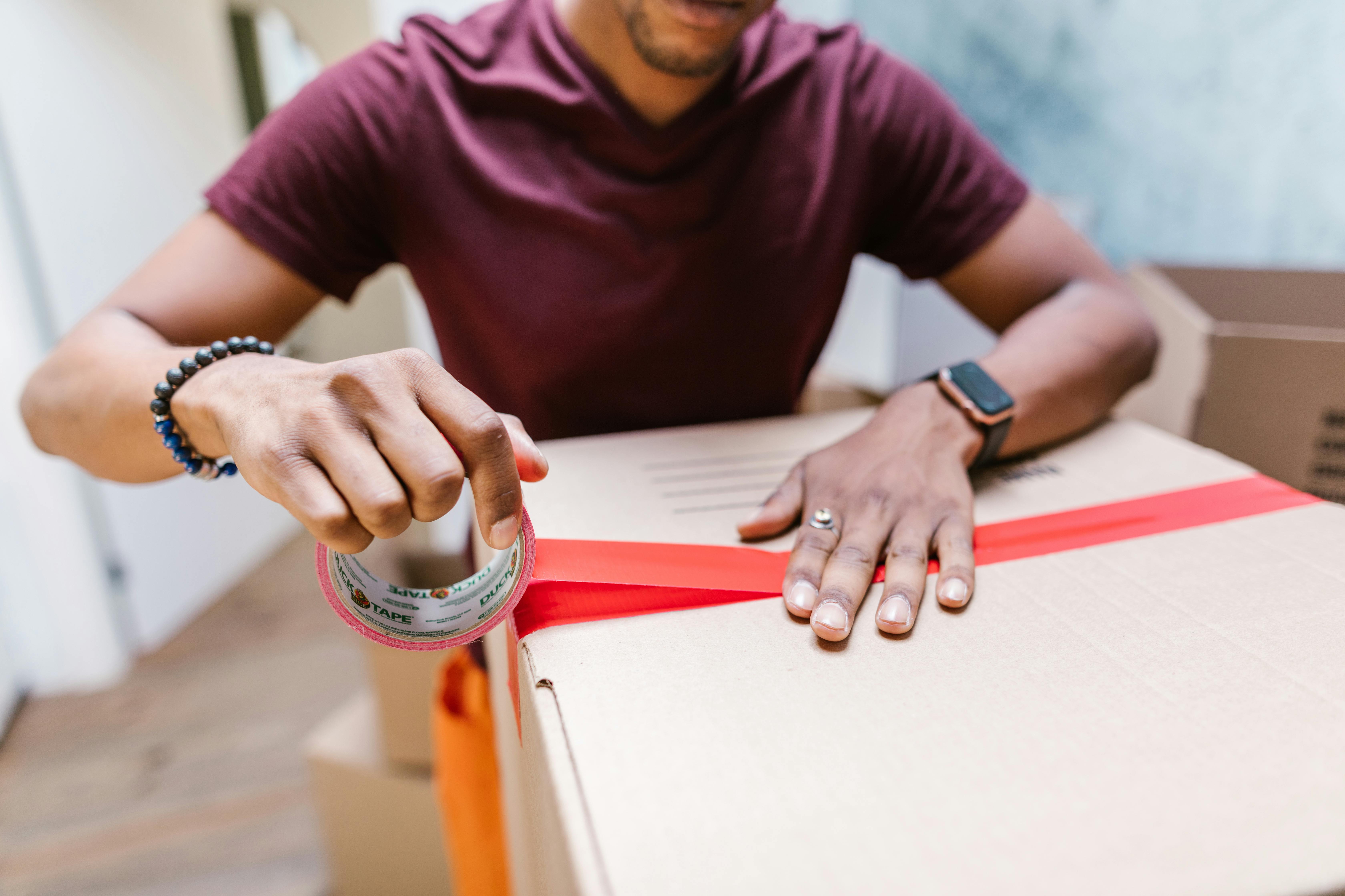 close up shot of a man putting tape on a cardboard box