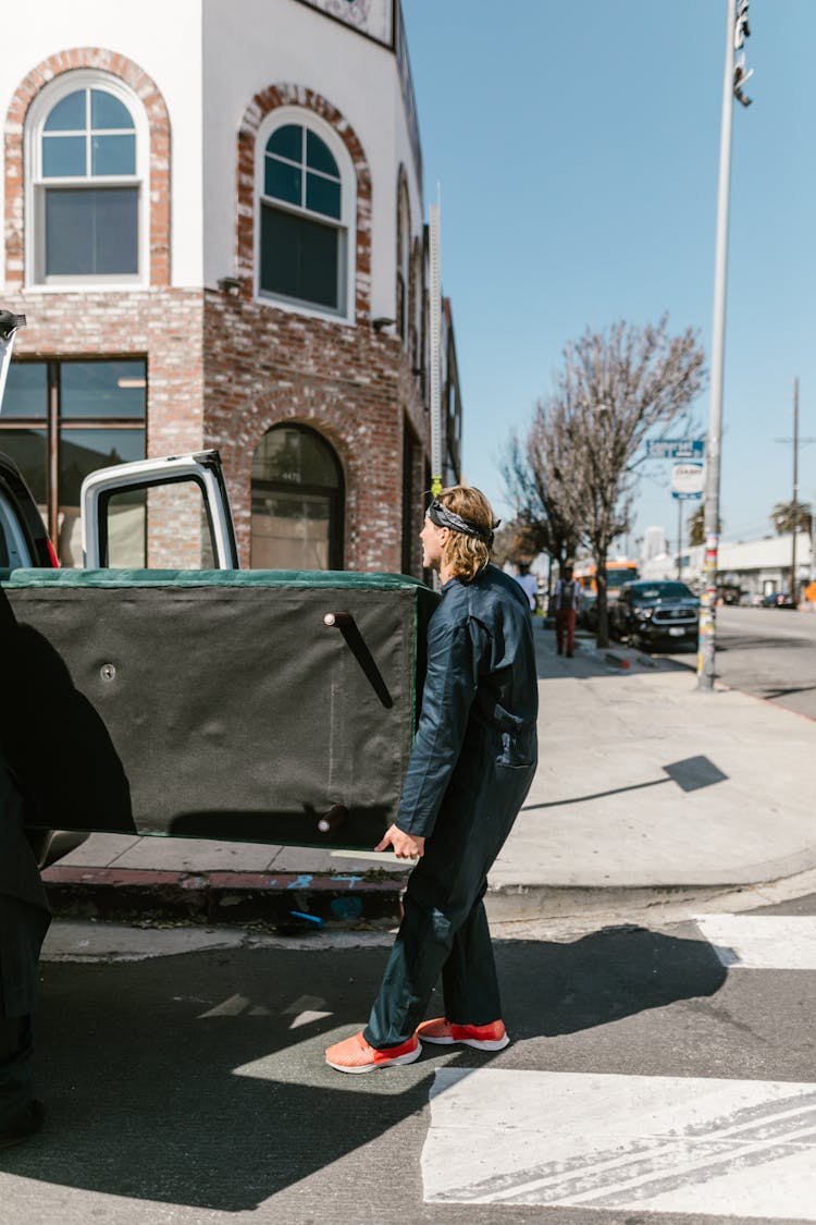 Full Shot Of A Man In Coverall Carrying A Couch