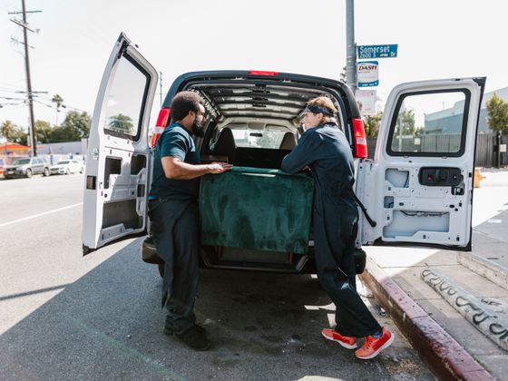 Two movers loading an old couch into the back of a van during a furniture removal - KD Junk, Waxhaw NC