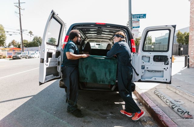 Two movers loading an old couch into the back of a van during a furniture removal - KD Junk, Waxhaw NC