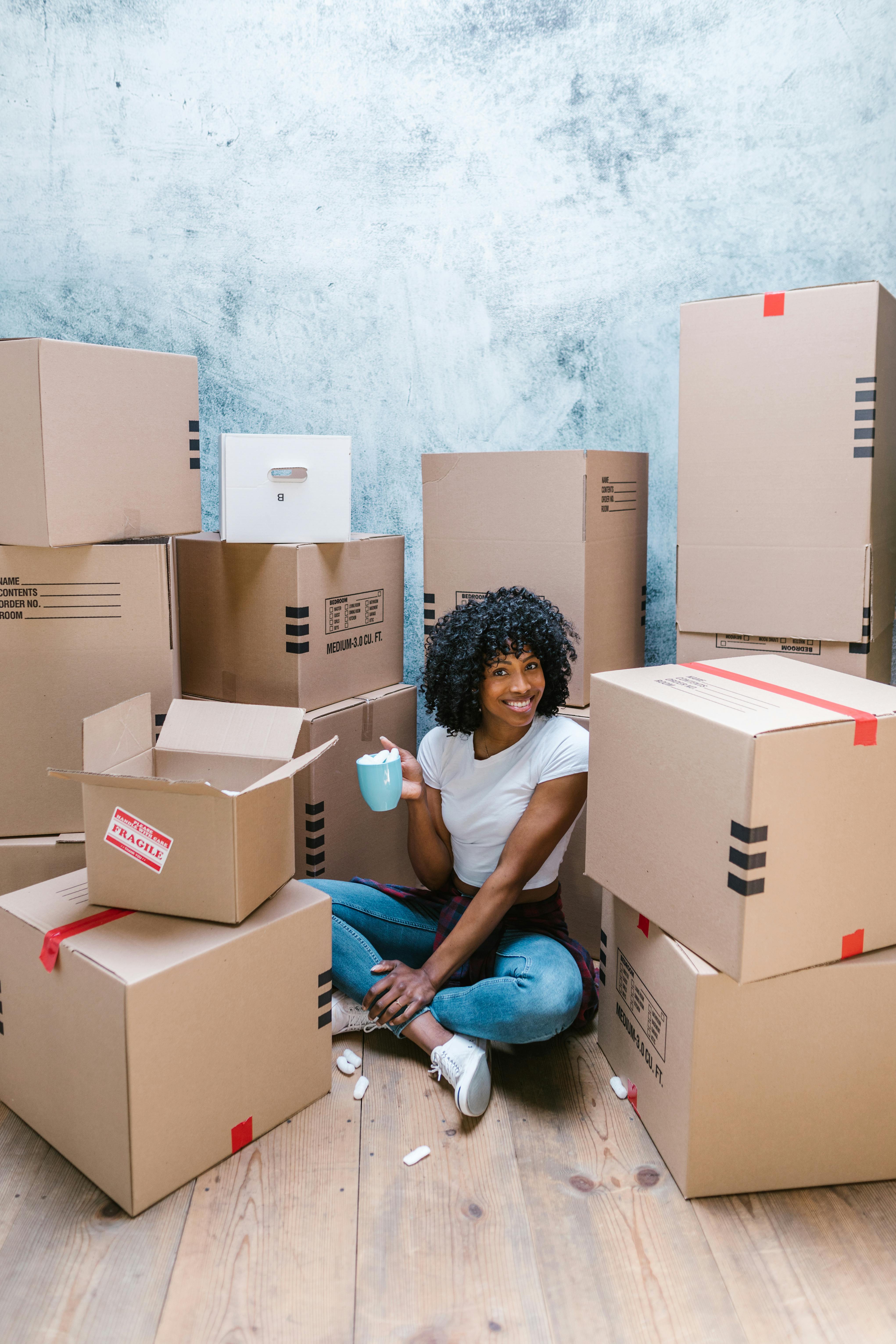 woman in white t shirt sitting on brown cardboard boxes