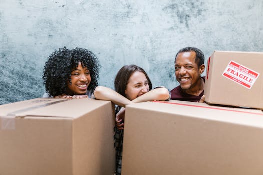 Three friends happily moving boxes into their new home, ready for a fresh start.