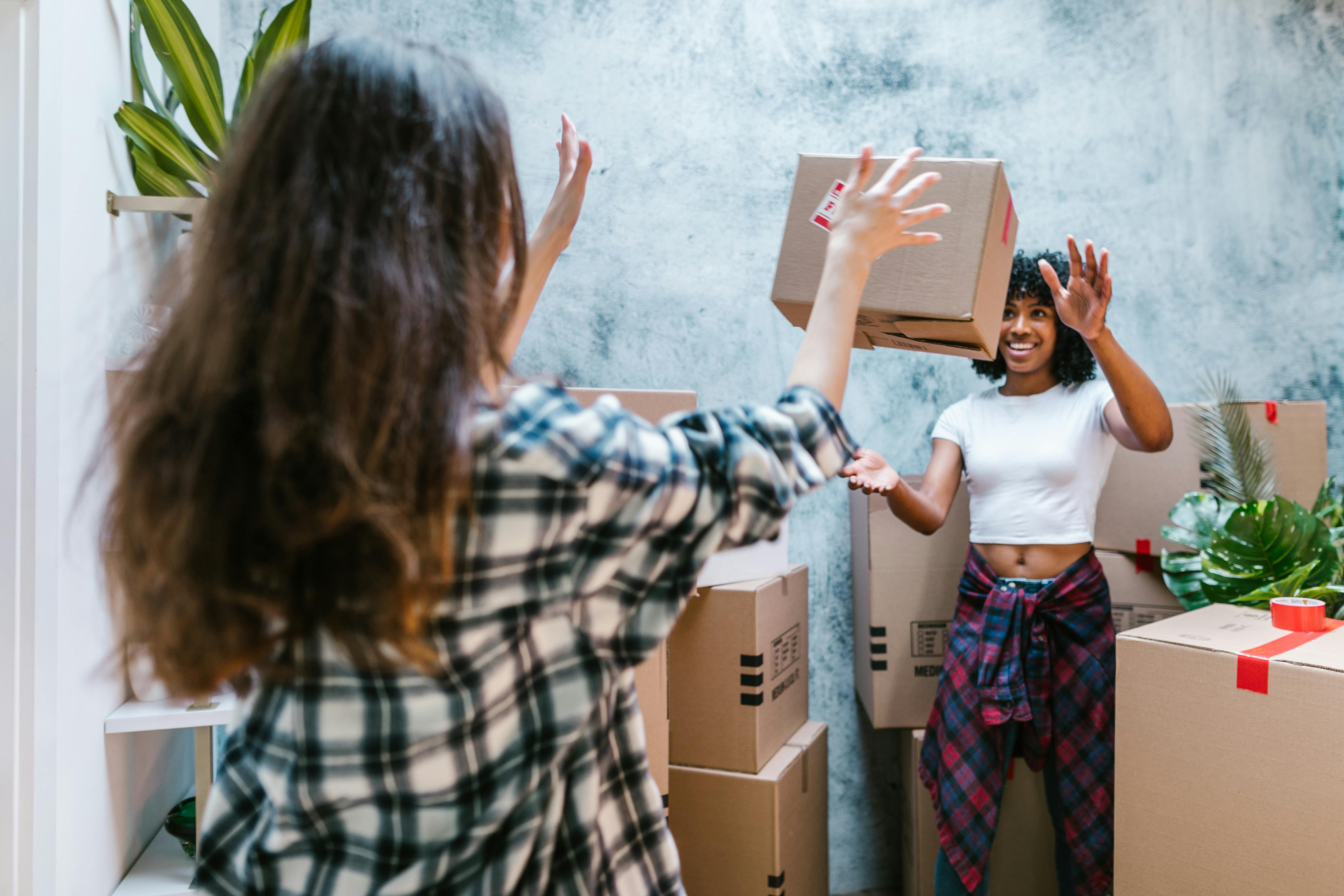 woman throwing moving box to friend