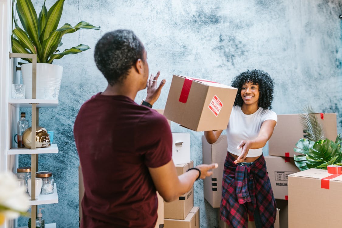 A woman handling over the box to a man while moving