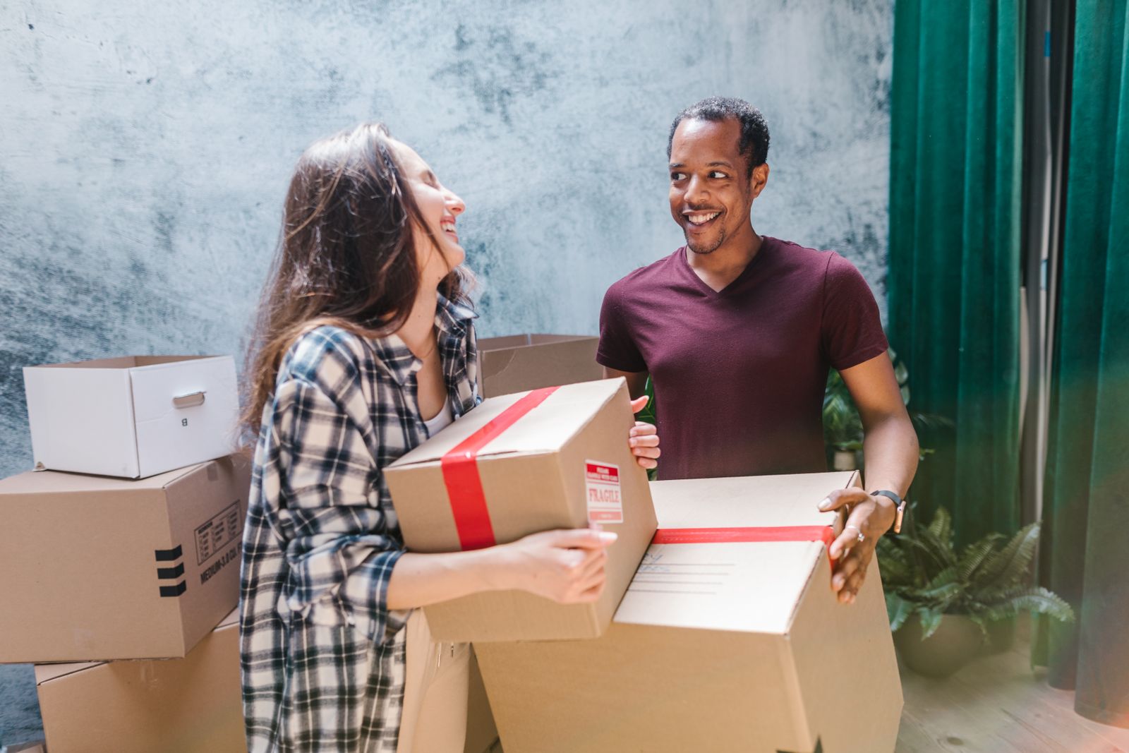 Couple carrying moving boxes out of a house