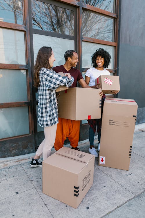 Free Young adults carry boxes into a modern apartment during their moving day. Stock Photo