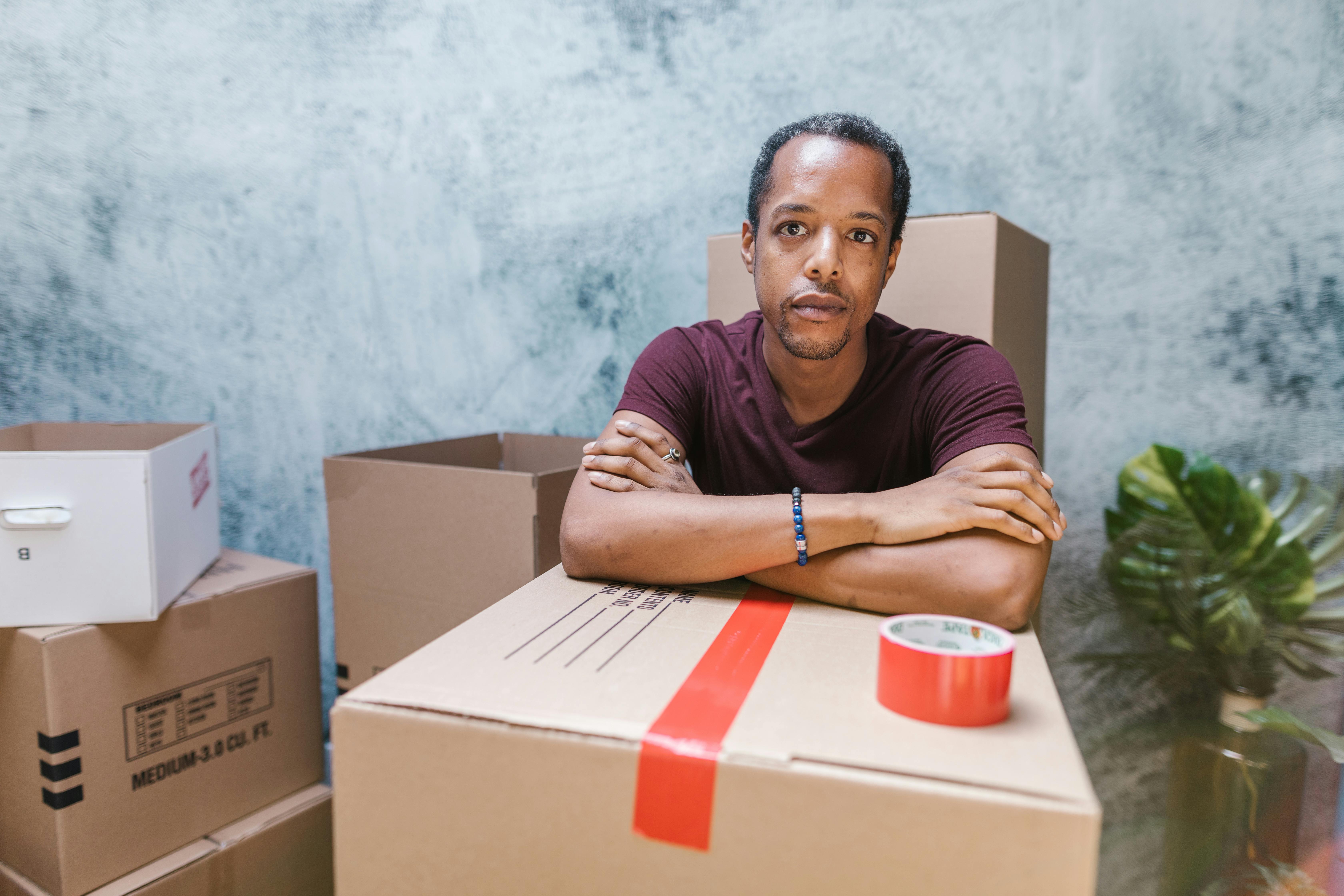 close up shot of man in maroon shirt near cardboard boxes