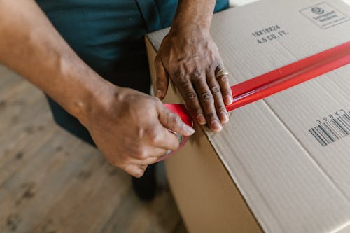 Close-Up Shot of a Person Putting Tape on a Cardboard Box