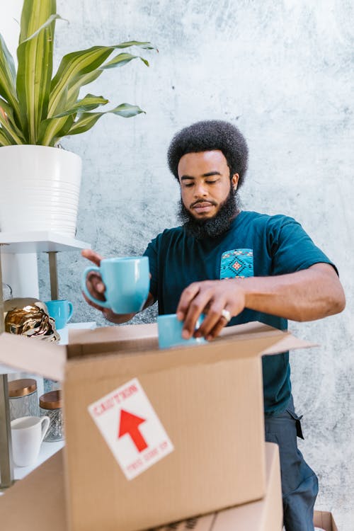 Free Man Packing Coffee Mugs in a Carboard Box Stock Photo