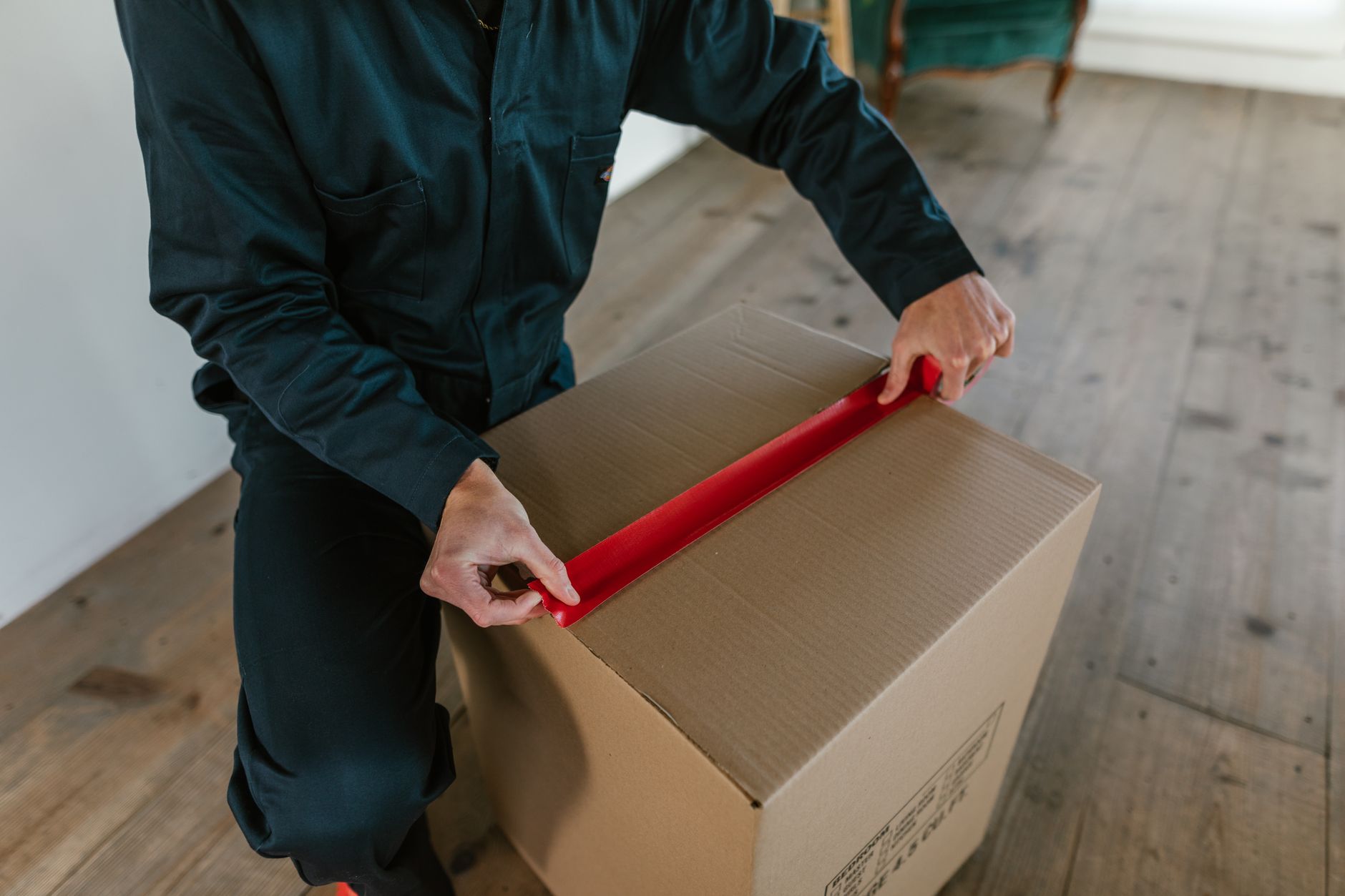 courier sealing a fragile parcel with packing tape and fragile label in a fulfillment center