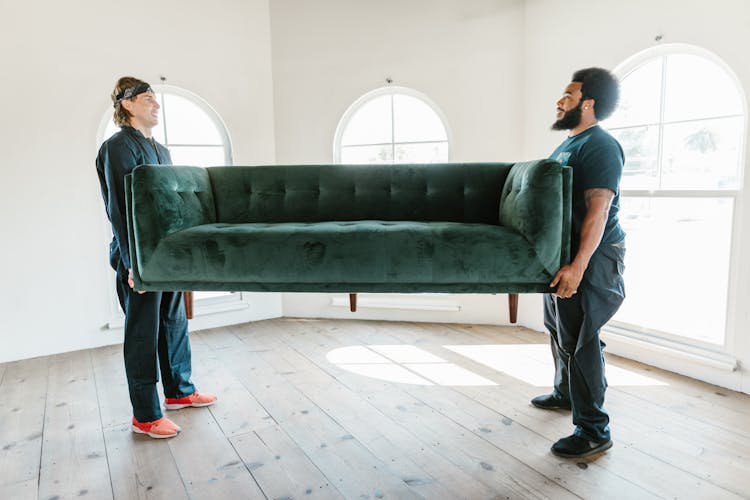 Close-Up Shot Of Men Carrying A Couch 