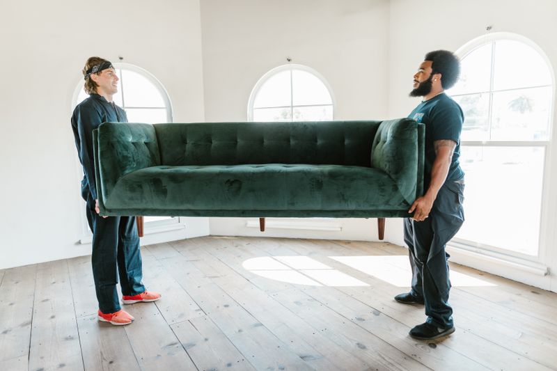 Two Lampard movers lifting a sofa together during a household move