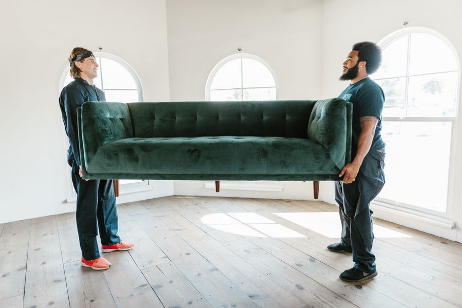 Raymo removalists carefully carrying a couch on moving day