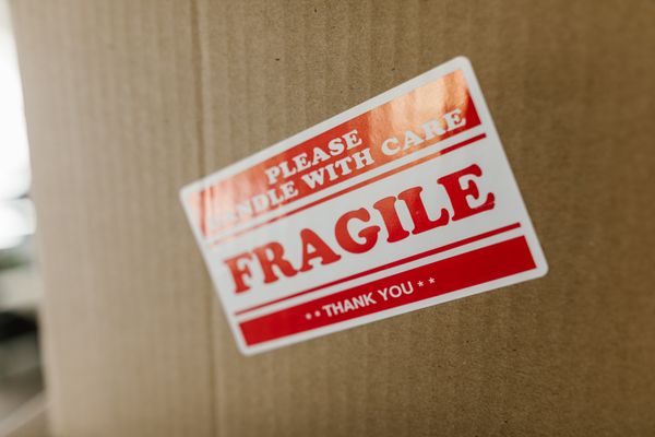 Fragile handle with care sticker on a cardboard moving box, illustrating moving insurance and valuation coverage